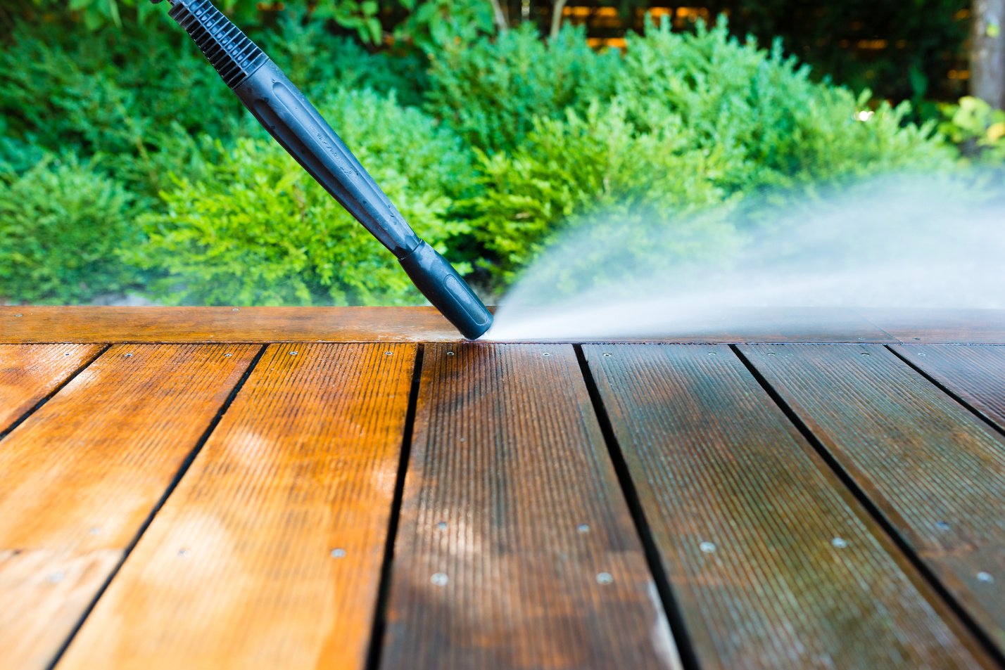 cleaning terrace with a power washer - high water pressure cleaner on wooden terrace surface